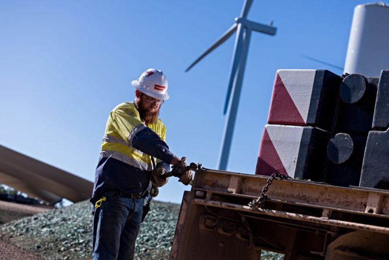 Employee undertaking wind farm operations, with wind turbine in background